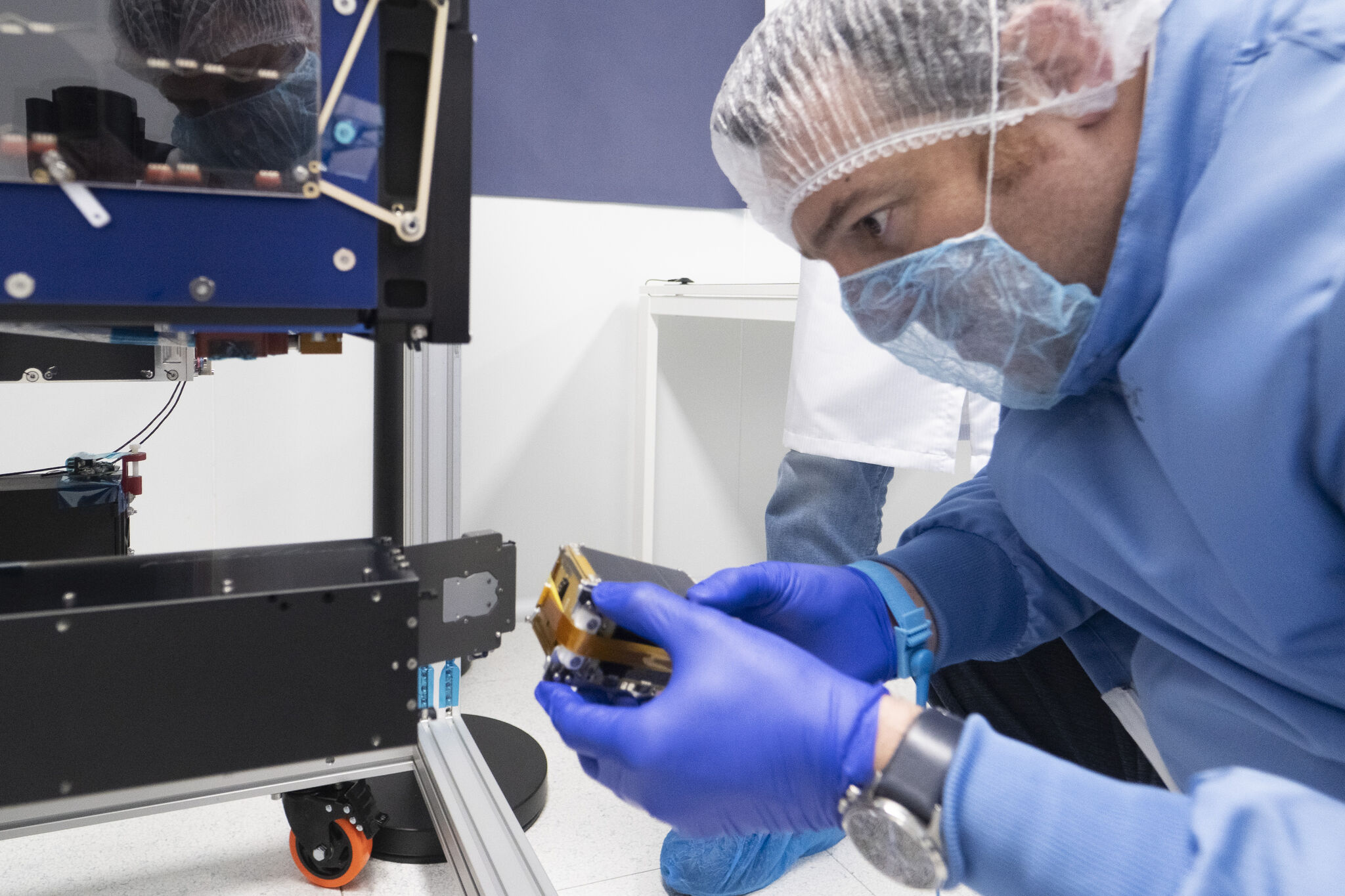Técnico con traje de sala limpia integrando un pequeño satélite en la estructura del OTV